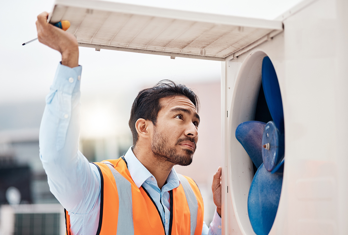 Technician inspecting an air conditioner unit during a repair service.